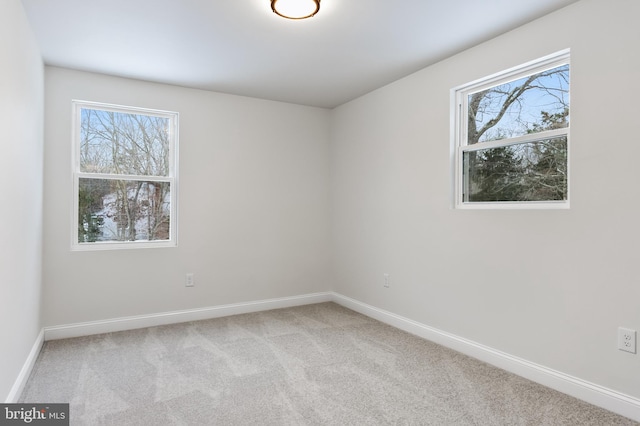 empty room with carpet, a healthy amount of sunlight, and baseboards