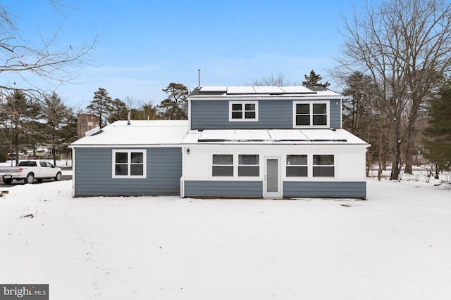 snow covered rear of property with solar panels