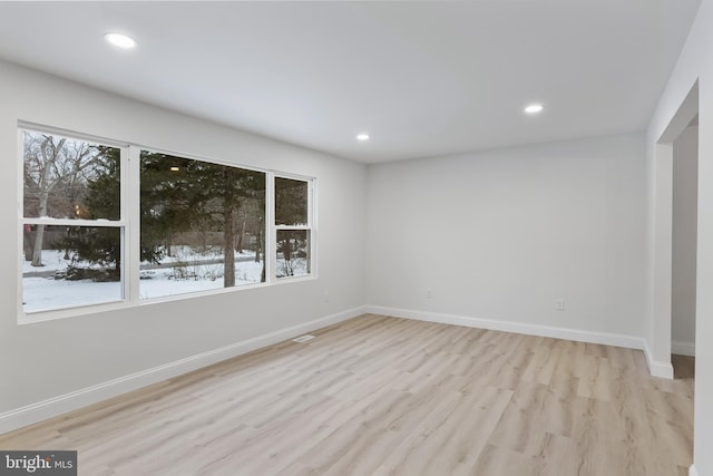 empty room featuring a wealth of natural light, baseboards, and wood finished floors