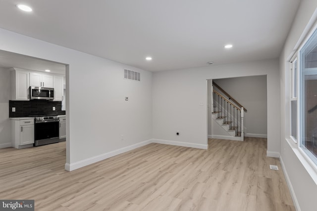 interior space featuring recessed lighting, visible vents, baseboards, stairway, and light wood-type flooring