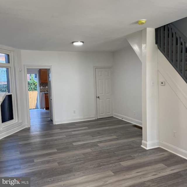 interior space with stairs, dark wood-style flooring, and baseboards