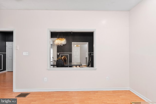 interior space featuring baseboards, visible vents, wood finished floors, and an inviting chandelier