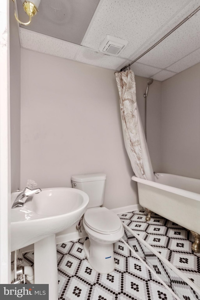 full bath with toilet, tile patterned floors, a drop ceiling, and baseboards