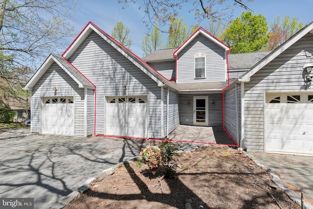 view of front of property with an attached garage, roof with shingles, and aphalt driveway