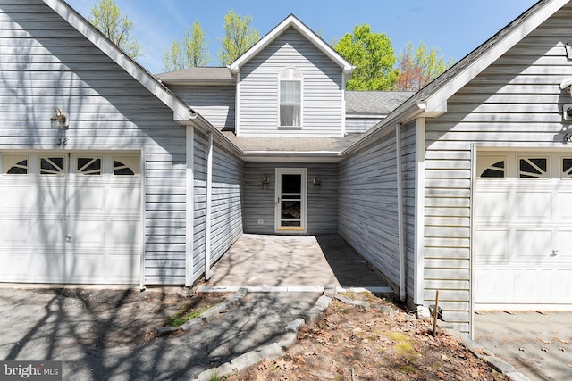 property entrance featuring a garage and roof with shingles