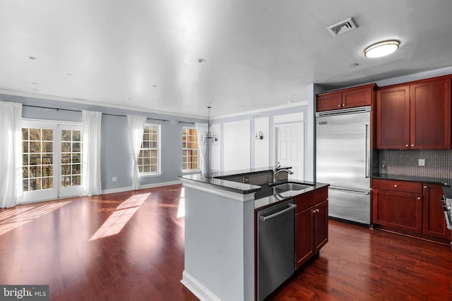 kitchen featuring visible vents, dark wood-style flooring, a sink, stainless steel appliances, and dark countertops