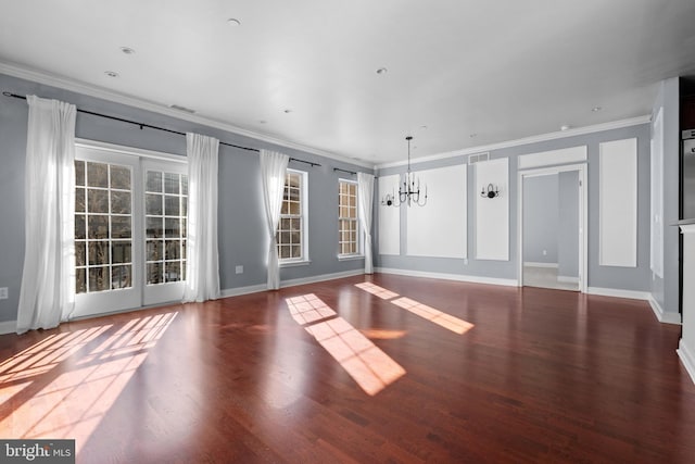 unfurnished living room with a notable chandelier, crown molding, baseboards, and wood finished floors