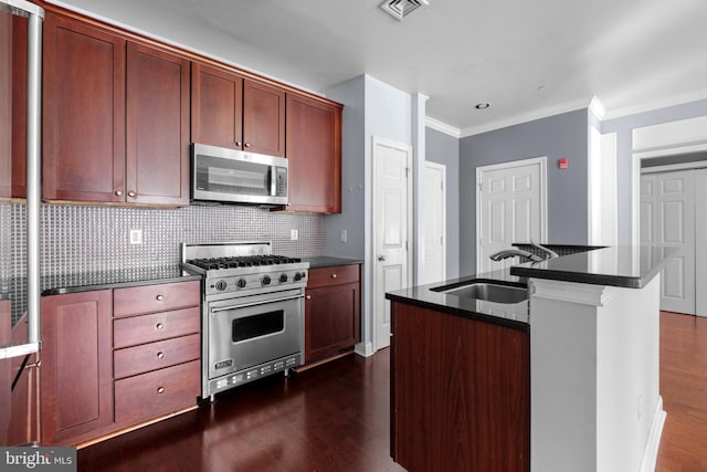 kitchen featuring dark countertops, visible vents, dark wood-type flooring, stainless steel appliances, and a sink