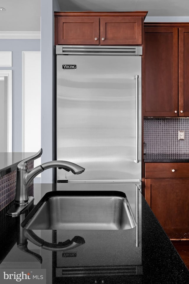 details with crown molding, tasteful backsplash, built in refrigerator, and a sink