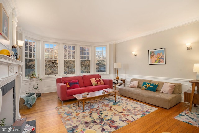 living area with a fireplace with flush hearth, a wainscoted wall, wood-type flooring, and ornamental molding