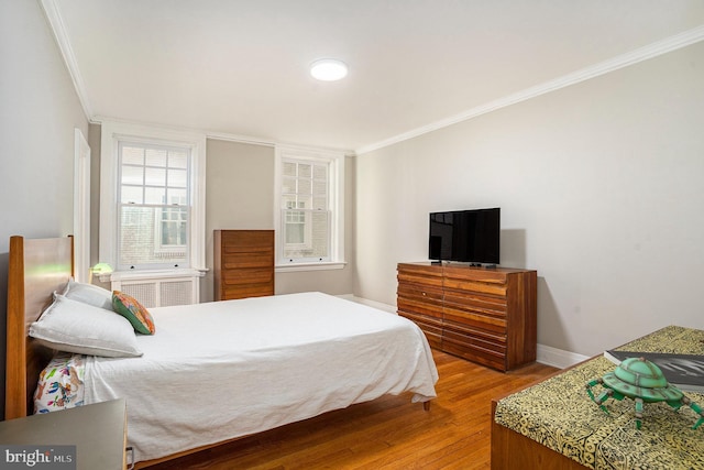 bedroom with wood finished floors, baseboards, and ornamental molding