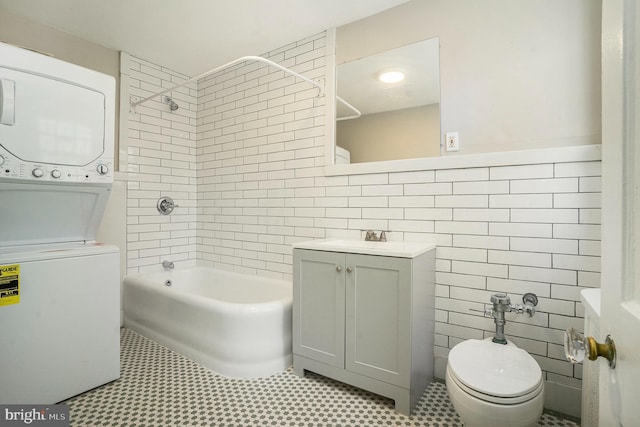 bathroom featuring vanity,  shower combination, stacked washer / drying machine, tile walls, and toilet