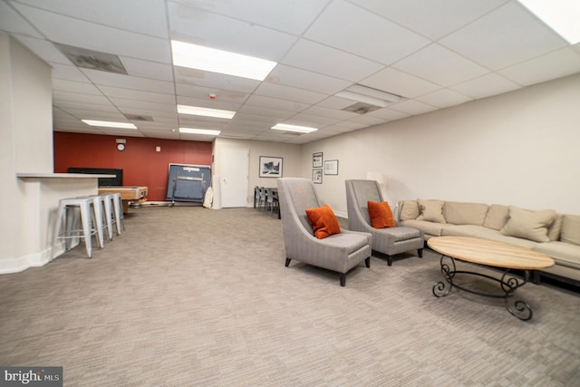 carpeted living area featuring visible vents, baseboards, and a drop ceiling