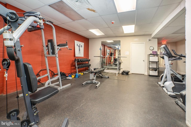 workout area featuring wooden walls, a drop ceiling, and visible vents