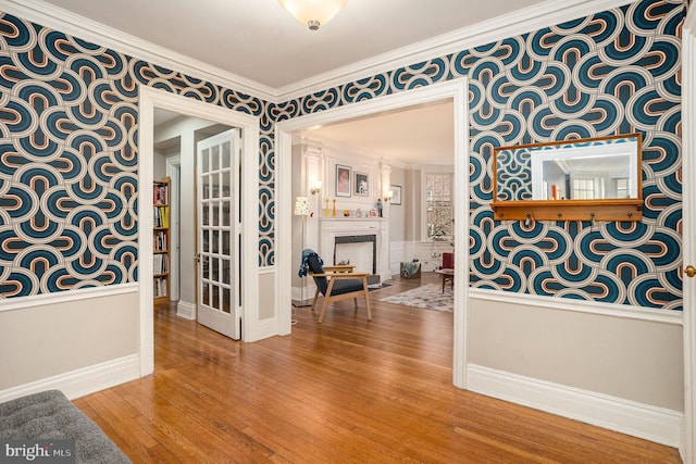 unfurnished dining area with baseboards, a fireplace, crown molding, and hardwood / wood-style flooring