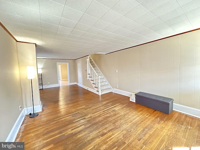 interior space featuring stairway, baseboards, wood finished floors, and crown molding