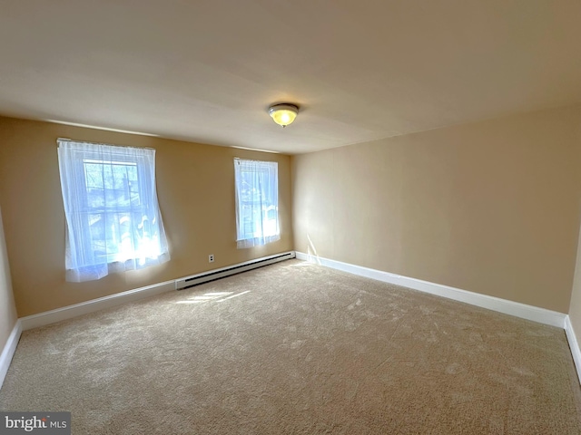 spare room with carpet flooring, a baseboard heating unit, and baseboards