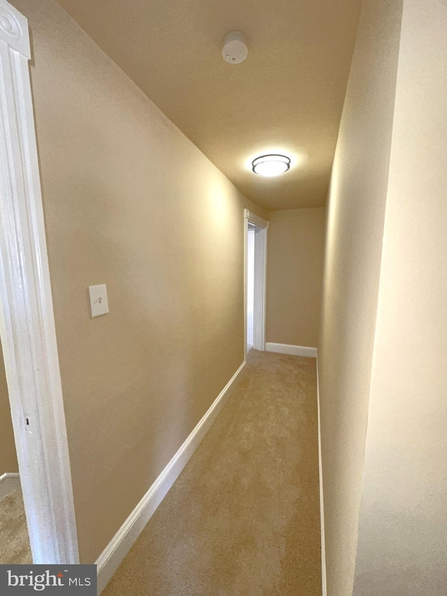 hallway featuring carpet flooring and baseboards