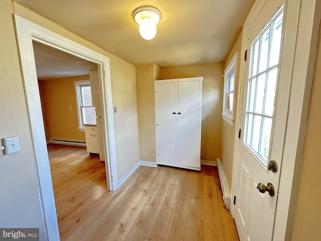 doorway to outside featuring a baseboard heating unit, light wood-style flooring, baseboards, and baseboard heating