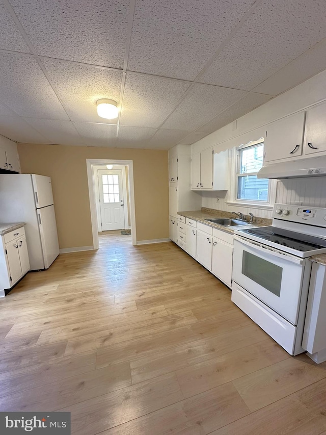 kitchen featuring under cabinet range hood, a healthy amount of sunlight, white appliances, and white cabinets