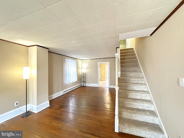 unfurnished living room with stairs, hardwood / wood-style flooring, crown molding, and baseboard heating