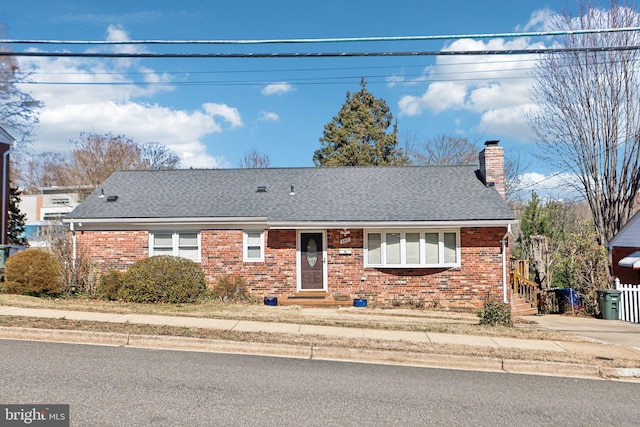 ranch-style home with a chimney, brick siding, and a shingled roof