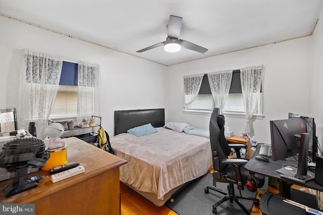 bedroom featuring multiple windows, ceiling fan, and wood finished floors