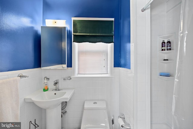 bathroom with a wainscoted wall, toilet, tile walls, and shower / bathtub combination with curtain