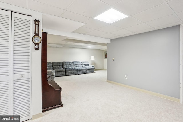 living room featuring baseboards, a paneled ceiling, and carpet