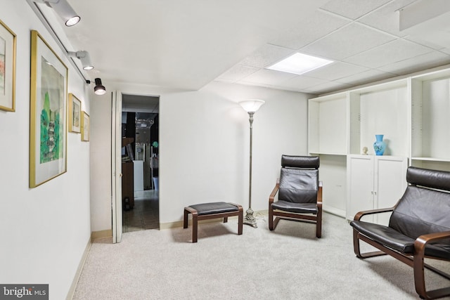 living area featuring a paneled ceiling and carpet