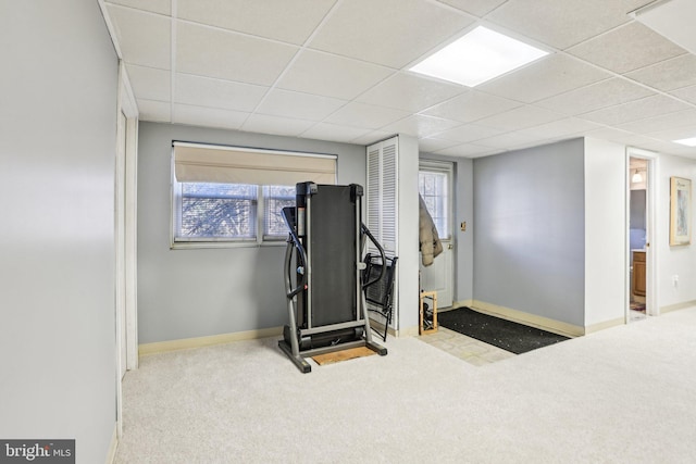 exercise room featuring baseboards, a paneled ceiling, and carpet