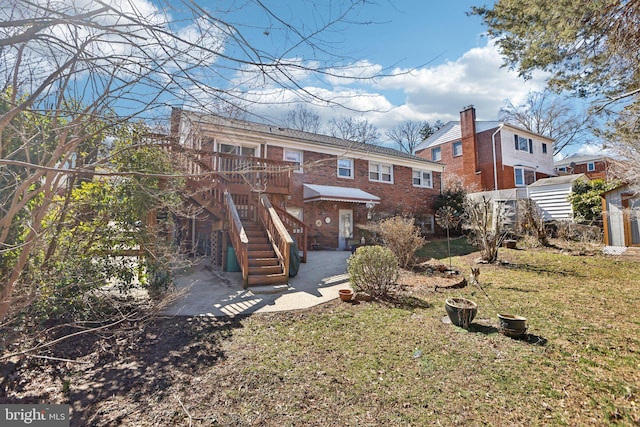 back of house featuring a yard, a patio, brick siding, and stairway