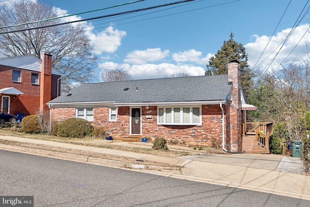 view of front of home with a chimney, brick siding, and a shingled roof