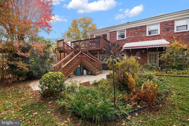 back of property with brick siding, a deck, and stairs