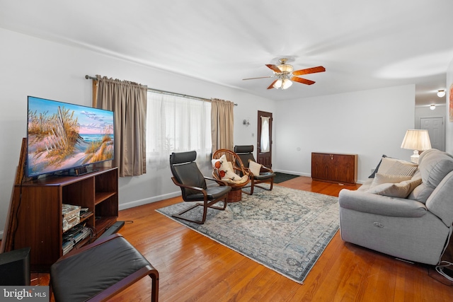 living area featuring a ceiling fan, wood finished floors, and baseboards