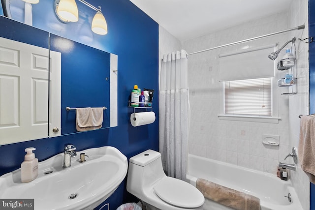 bathroom with toilet, shower / bath combo with shower curtain, and a sink