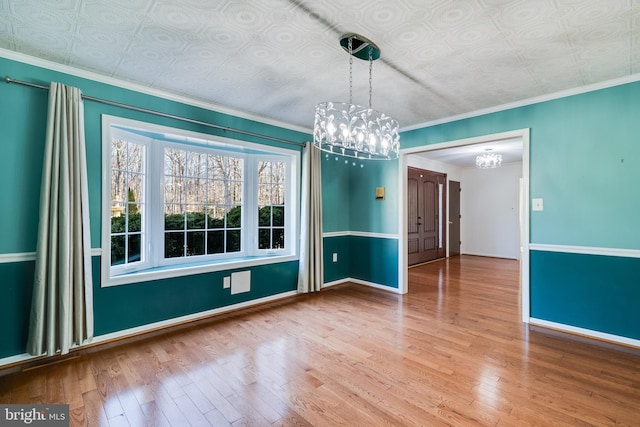 empty room with wood-type flooring, baseboards, an ornate ceiling, and ornamental molding