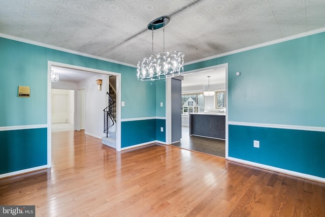 unfurnished room featuring wood finished floors, baseboards, an ornate ceiling, and ornamental molding