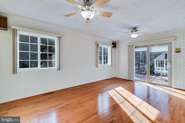 spare room featuring brick wall, a textured ceiling, and hardwood / wood-style floors