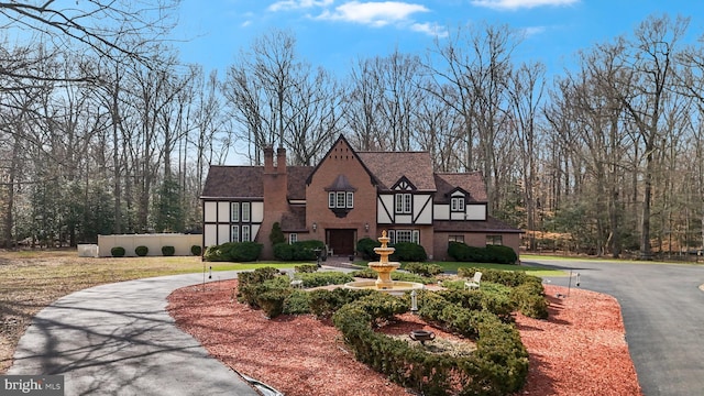 tudor house featuring aphalt driveway and a chimney