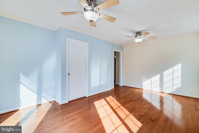 empty room with ceiling fan, baseboards, and wood finished floors