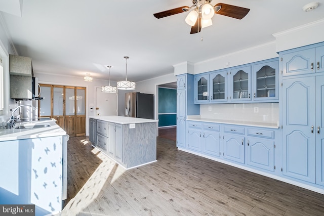 kitchen with a center island, glass insert cabinets, light countertops, stainless steel appliances, and a sink