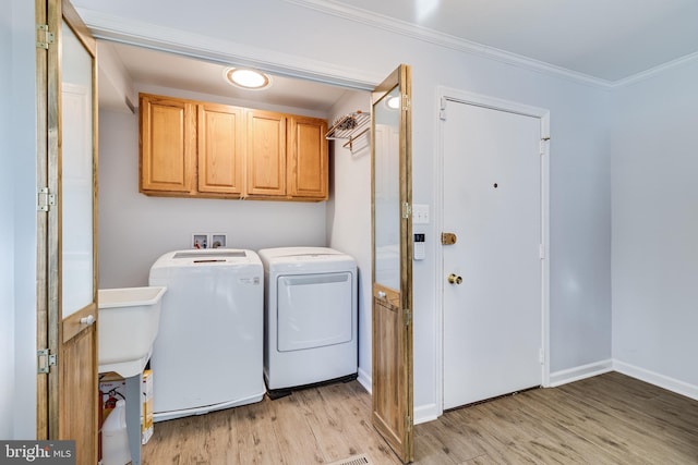 laundry area with baseboards, light wood-type flooring, ornamental molding, cabinet space, and separate washer and dryer