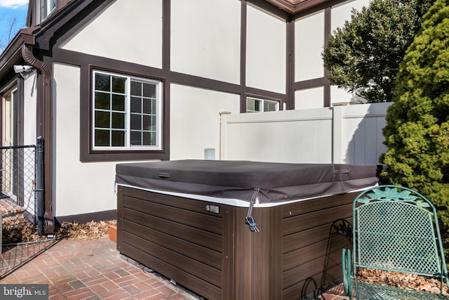 view of patio / terrace with a hot tub and fence