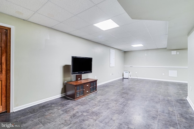 unfurnished living room featuring a paneled ceiling and baseboards