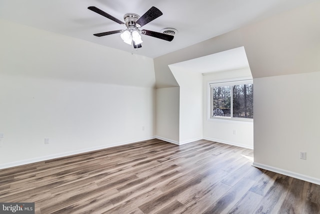 additional living space featuring visible vents, baseboards, vaulted ceiling, wood finished floors, and a ceiling fan