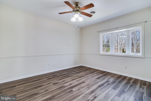 spare room with wood finished floors, baseboards, visible vents, ceiling fan, and ornamental molding