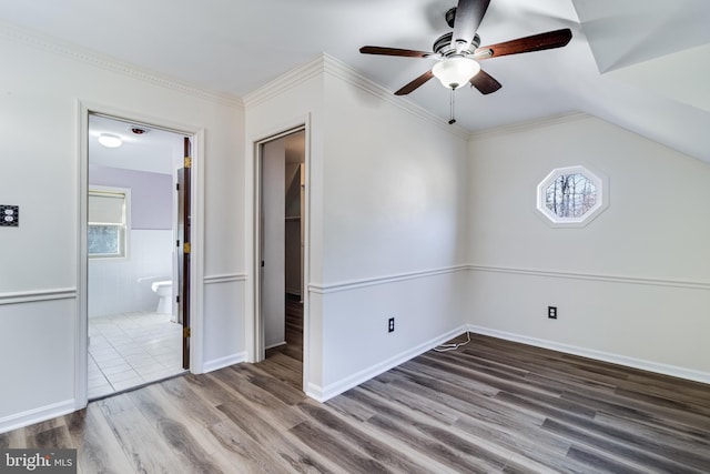 unfurnished bedroom with ornamental molding, ensuite bath, a ceiling fan, and wood finished floors