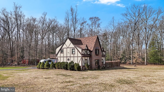 view of side of property with a yard, fence, and a shingled roof