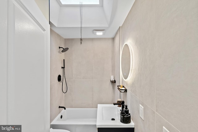 bathroom with vanity, tile walls, and tub / shower combination